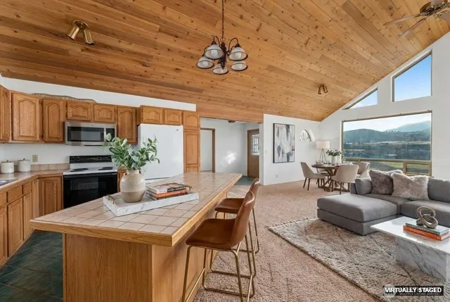 a kitchen with stainless steel appliances granite countertop a stove a sink dishwasher a dining table and chairs with wooden floor