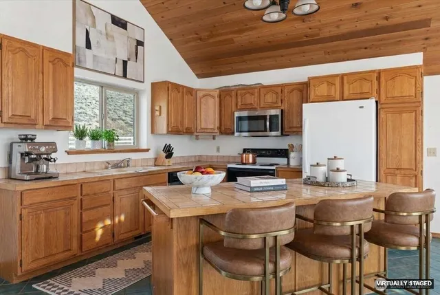 a kitchen with stainless steel appliances kitchen island granite countertop a sink a stove cabinets dining table and chairs