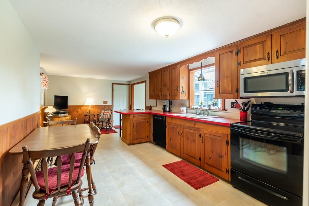 19 Willow Road Boxford, MA 01921 - Photo 11 of 32 a open kitchen with stainless steel appliances granite countertop a stove top oven a sink dishwasher a dining table and chairs with wooden floor