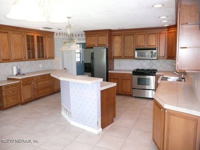 329 Pablo Road Ponte Vedra Beach, FL 32082 - Photo 5 of 6 a kitchen with stainless steel appliances granite countertop a stove top oven a sink a refrigerator and white cabinets