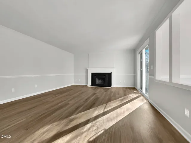 a view of an empty room and window and wooden floor