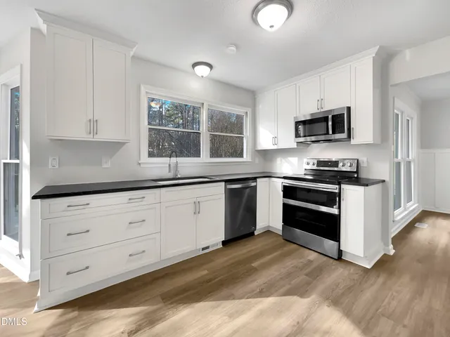 a kitchen with granite countertop white cabinets and stainless steel appliances