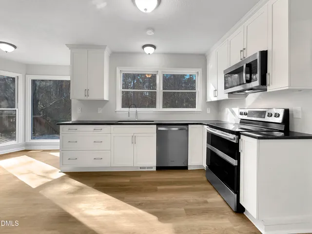 a kitchen with stainless steel appliances granite countertop a stove a sink and a microwave