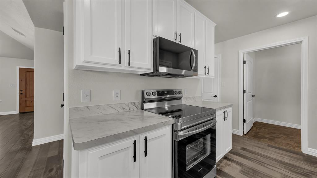 1830 Hitching Post Road Granbury, TX 76049 - Photo 16 of 34 a kitchen with white cabinets and stainless steel appliances