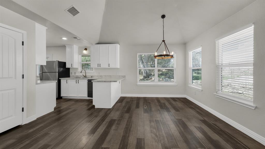 1830 Hitching Post Road Granbury, TX 76049 - Photo 9 of 34 a kitchen with stainless steel appliances a stove top oven a refrigerator a sink and white cabinets with wooden floor