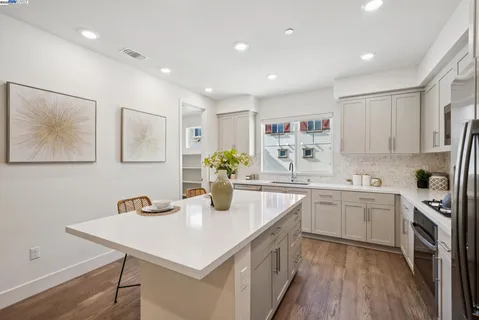 a kitchen with stainless steel appliances kitchen island granite countertop a sink a stove a dining table and chairs