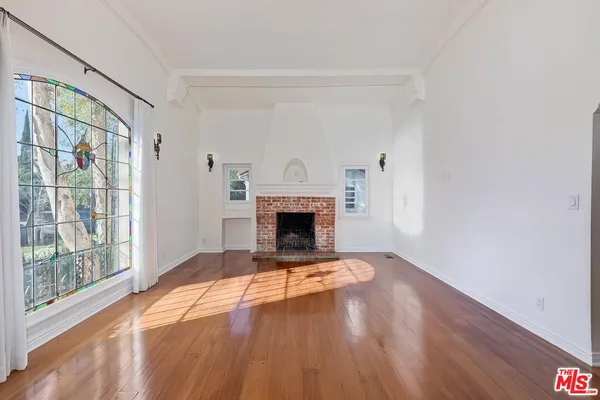 a view of empty room with wooden floor and fireplace