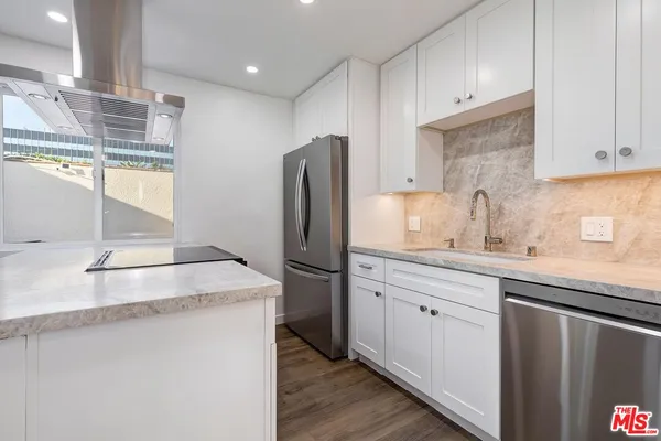 a kitchen with stainless steel appliances granite countertop a sink a refrigerator and a granite counter tops