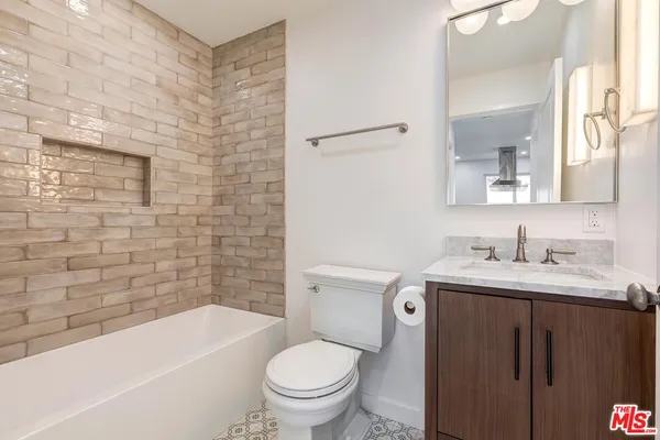 a bathroom with a granite countertop toilet a sink a mirror a bathtub and a shower