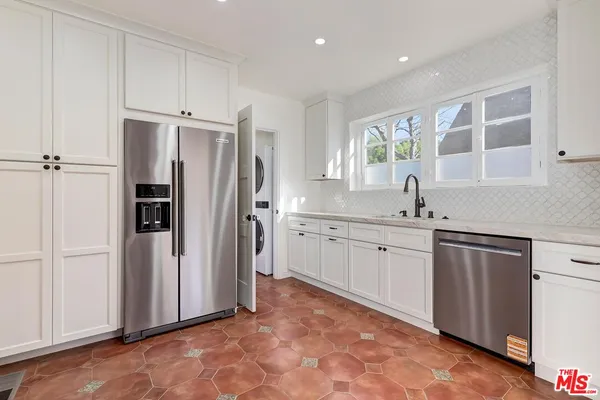a kitchen with white cabinets and refrigerator