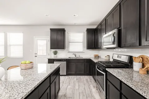 a kitchen with granite countertop stainless steel appliances a sink stove top oven and cabinets