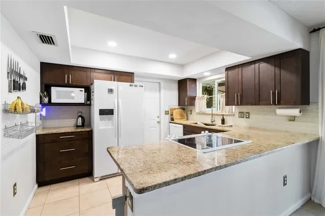 a kitchen with stainless steel appliances granite countertop a sink refrigerator and cabinets