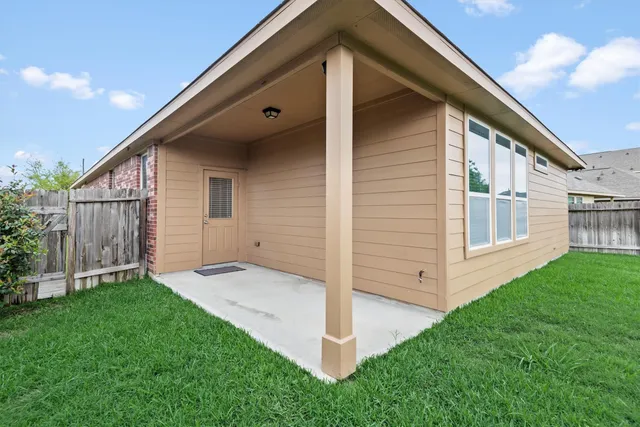 a view of backyard with large trees and wooden fence