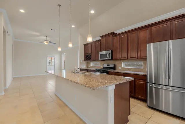 a kitchen with stainless steel appliances granite countertop a refrigerator a sink a stove a microwave and island