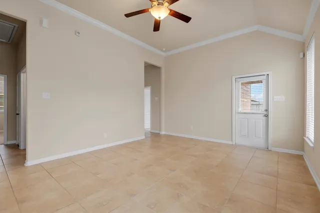 a view of an empty room with chandelier fan