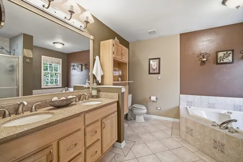 a spacious bathroom with a granite countertop sink a toilet and a mirror