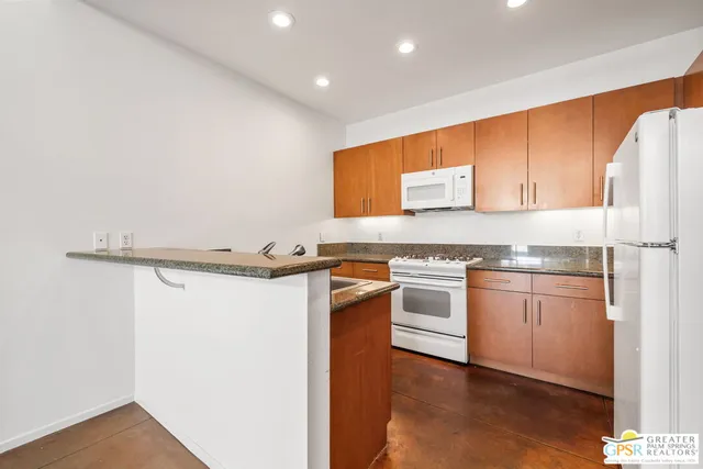a kitchen with granite countertop white cabinets and white appliances