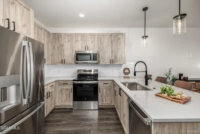 a kitchen with stainless steel appliances granite countertop a refrigerator a stove and a sink with wooden floor