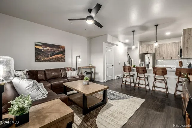 a living room with furniture kitchen view and a wooden floor