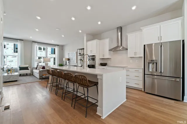 a kitchen with stainless steel appliances a refrigerator a stove a sink dishwasher a oven with white cabinets and wooden floor