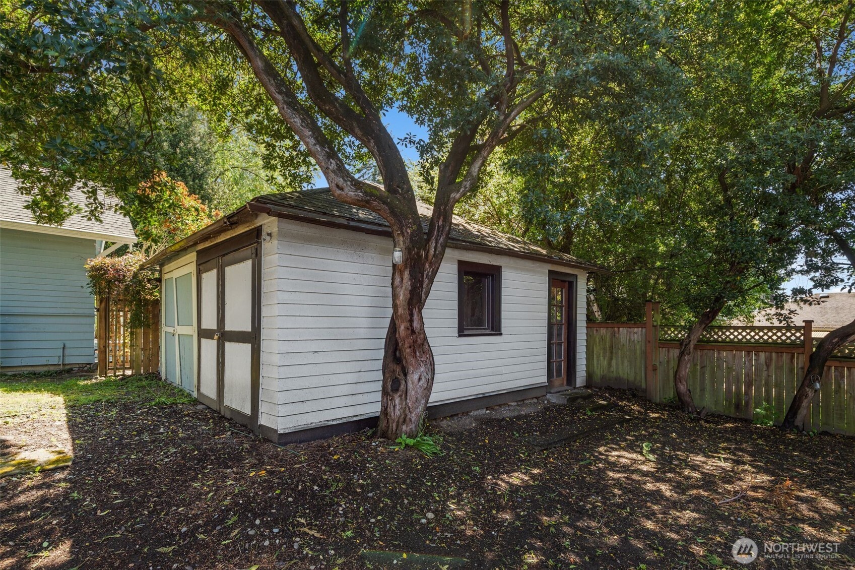 2125 North 90th Street Seattle, WA 98103 - Photo 26 of 29 a backyard of a house with large trees and wooden fence