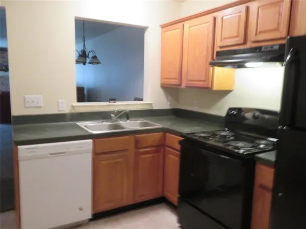 a kitchen with granite countertop stainless steel appliances a stove sink and cabinets