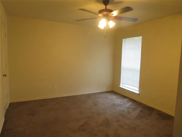 an empty room with a fan & a window