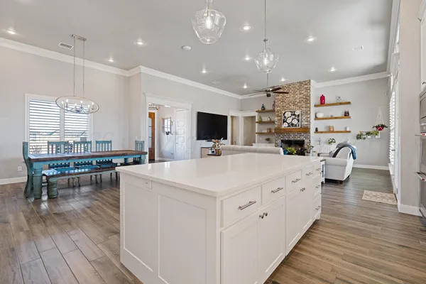 a kitchen with stainless steel appliances a refrigerator a stove a sink a dining table and chairs with wooden floor