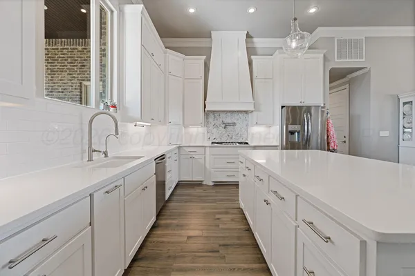 a large white kitchen with a large counter top appliances and cabinets
