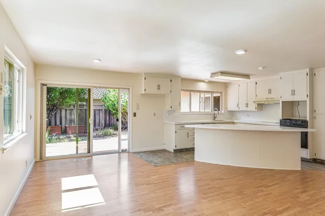 a open kitchen with white cabinets and wooden floor