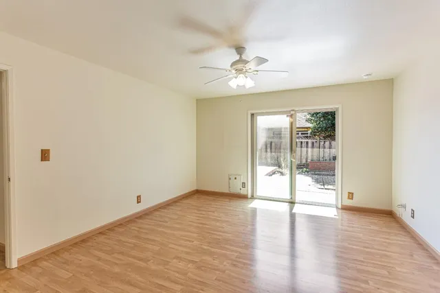 an empty room with wooden floor fan and windows