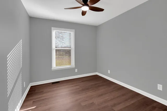 an empty room with wooden floor & windows