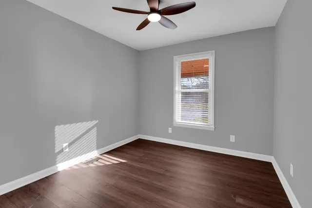 a view of an empty room with wooden floor and closet