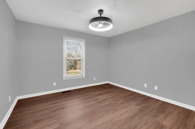 a view of an empty room with a window and wooden floor