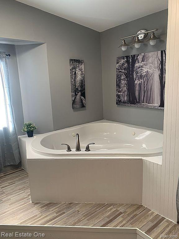 786 Chestnut Street Fowlerville, MI 48836 - Photo 11 of 19 Corner soaking tub with brushed nickel fixtures, gray wall paint, and wood-finish flooring