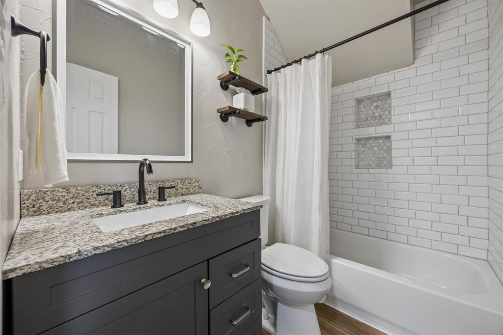 9217 Inverness Drive Rowlett, TX 75089 - Photo 24 of 40 Updated Secondary Bath — Granite counters, updated cabinetry, modern fixtures, and subway tile surround give this bath a polished, refreshed feel.