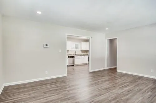 a view of an empty room with wooden floor and a window