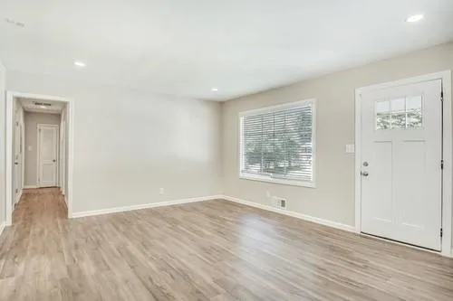 an empty room with wooden floor and windows