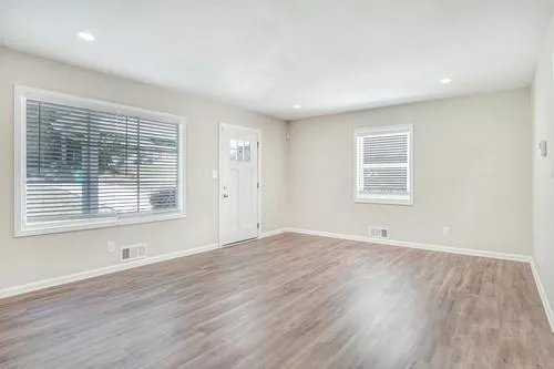 an empty room with wooden floor and windows