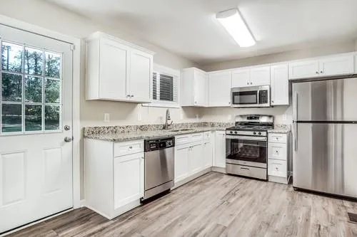 a kitchen with granite countertop white cabinets and stainless steel appliances