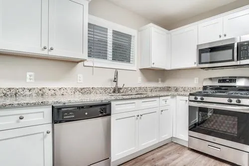a kitchen with granite countertop white cabinets and appliances