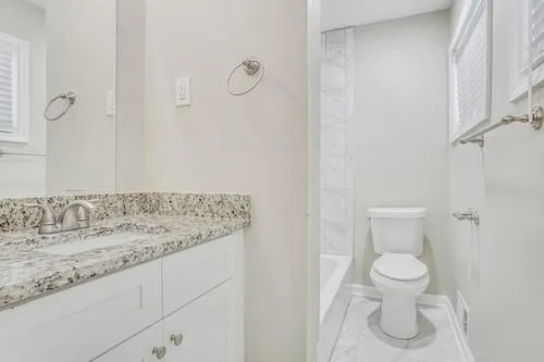 a bathroom with a granite countertop sink and a toilet