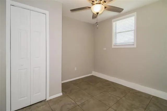 an empty room with a window and a chandelier fan