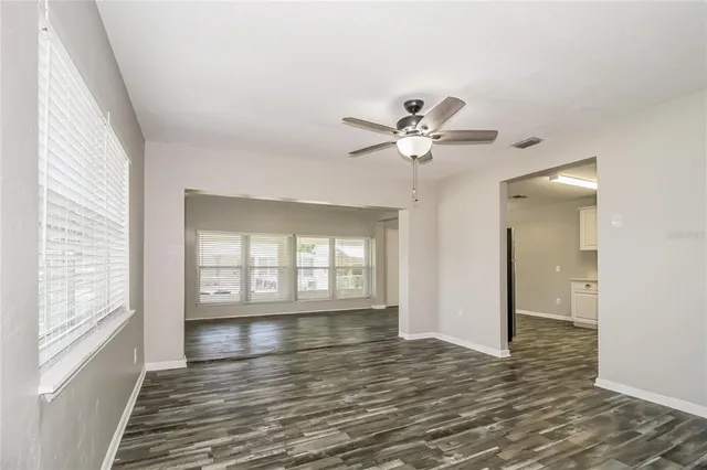 a view of an empty room with a window and wooden floor