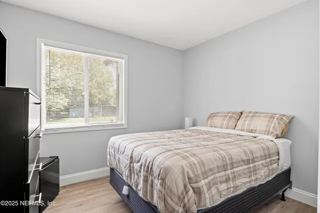 a bedroom with a bed next to a window with a tv
