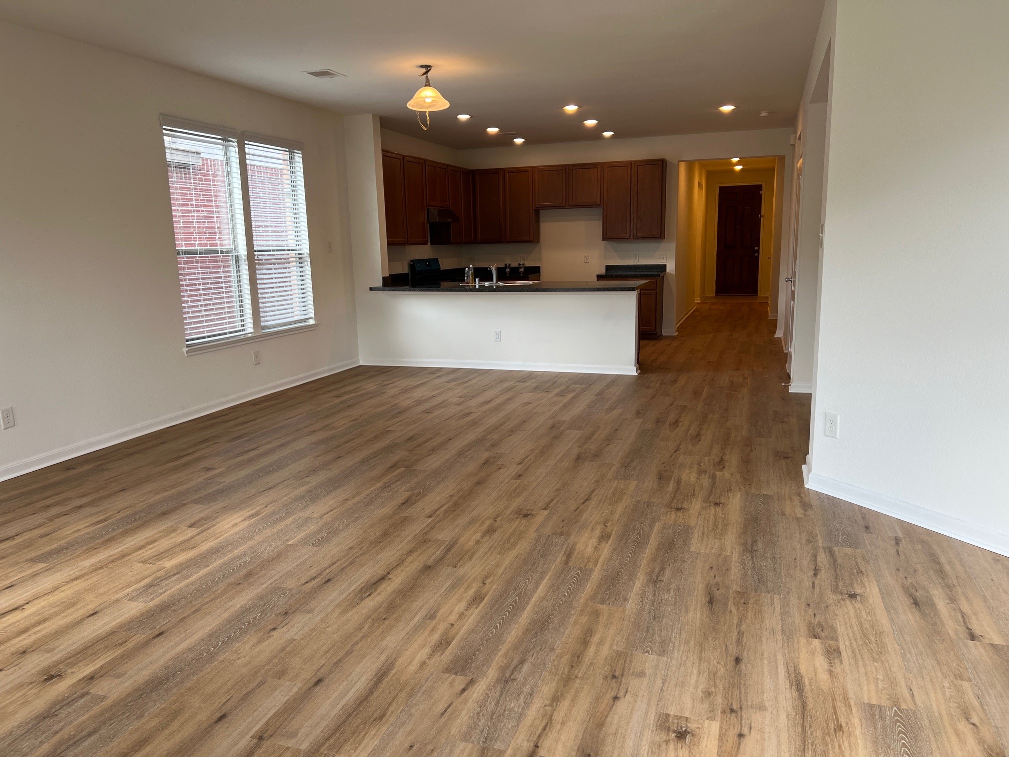 a view of kitchen with kitchen island a sink wooden floor and a living room view