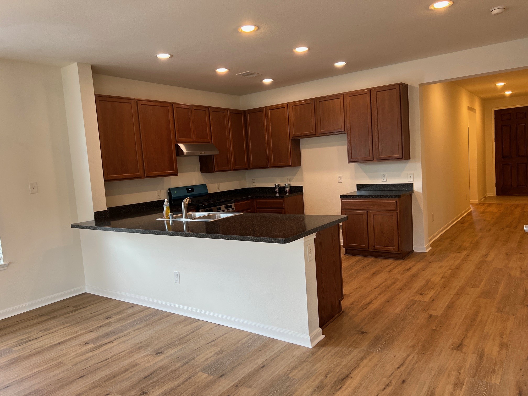 22511 Bellwick Ridge Lane Katy, TX 77449 - Photo 5 of 14 a kitchen with kitchen island granite countertop wooden cabinets a sink and a stove with wooden floor