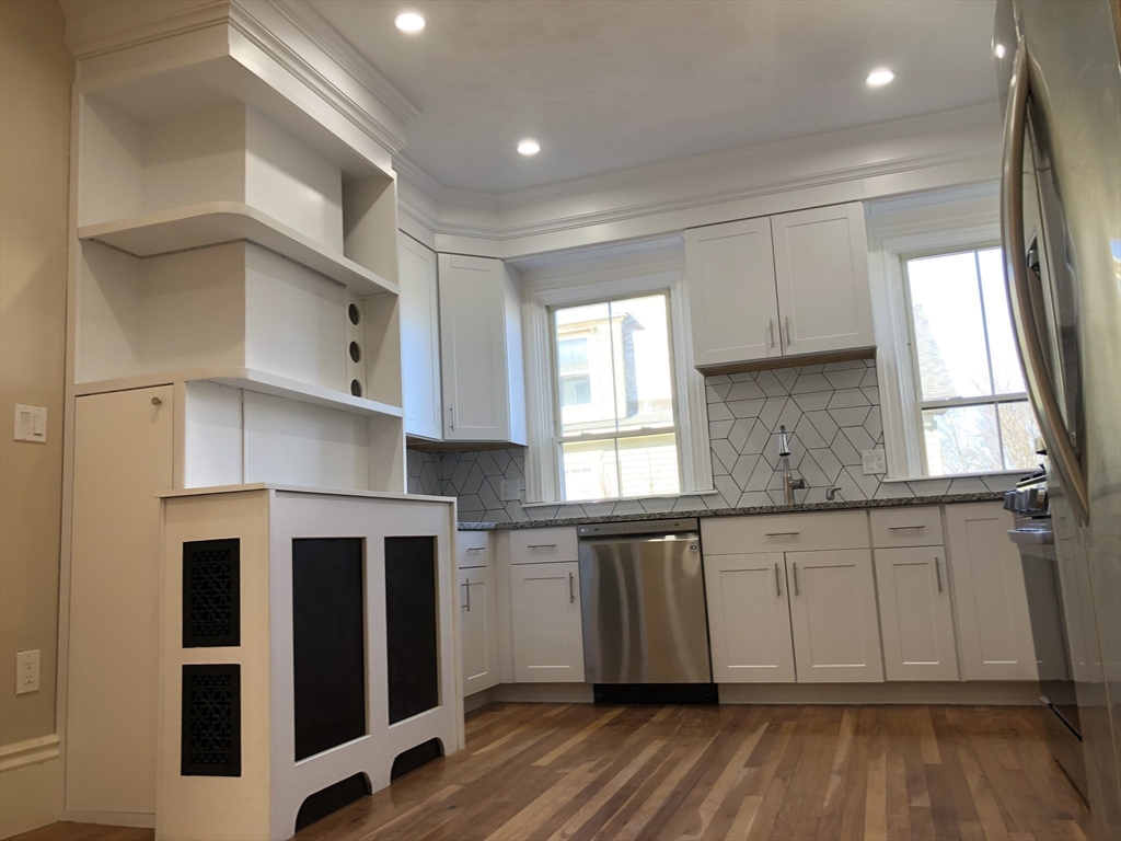 62 Thomas Street, Unit 2 New Bedford, MA 02740 - Photo 2 of 10 a kitchen with granite countertop a stove a sink and white cabinets with wooden floor