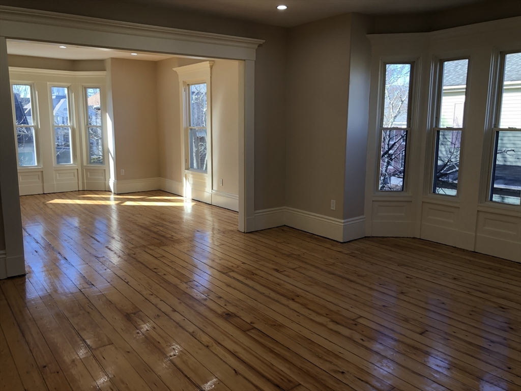 62 Thomas Street, Unit 2 New Bedford, MA 02740 - Photo 4 of 10 an empty room with wooden floor and windows