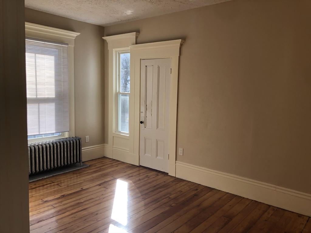 62 Thomas Street, Unit 2 New Bedford, MA 02740 - Photo 7 of 10 an empty room with wooden floor and windows